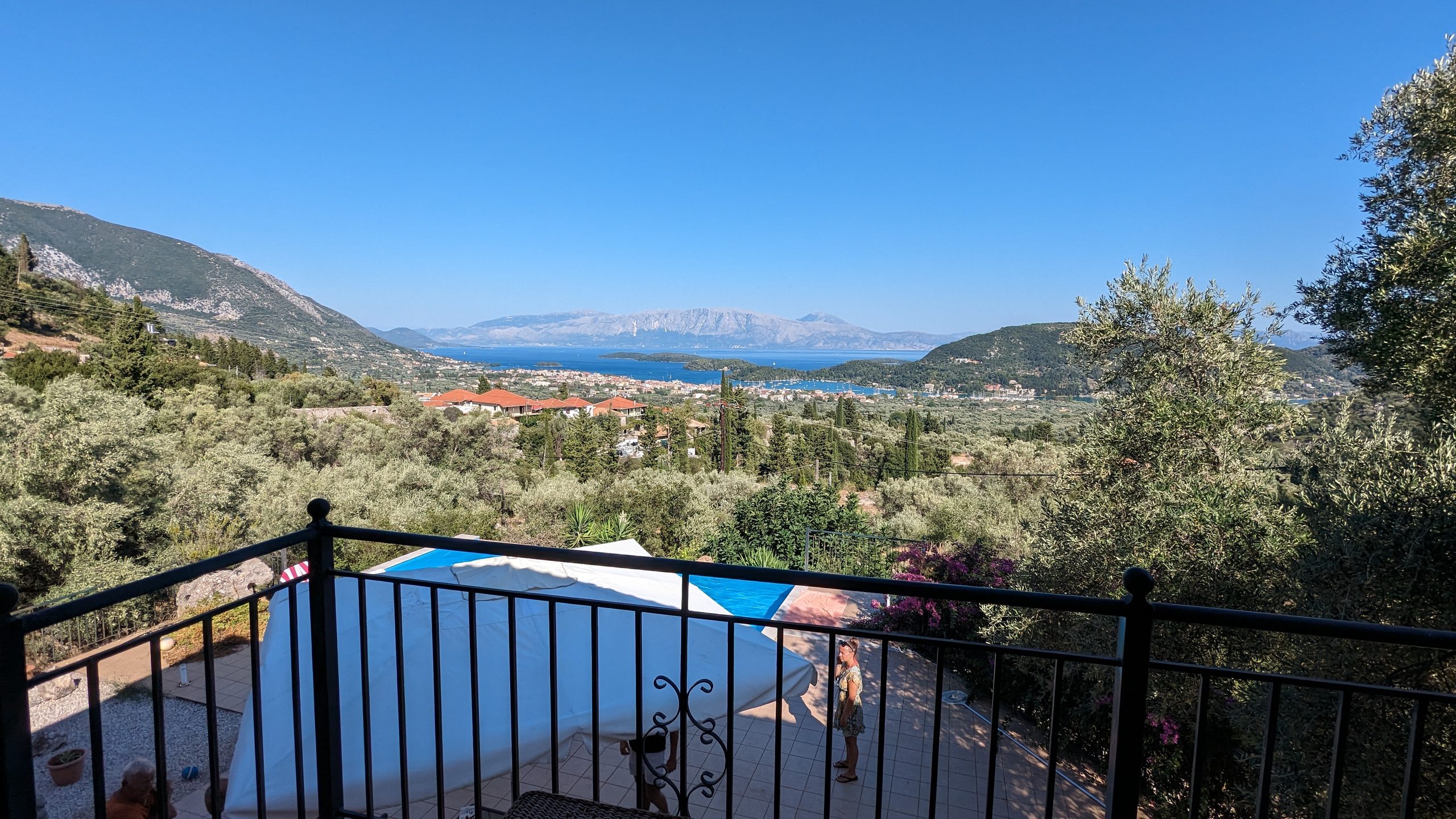 The view from a bedroom balcony, over the pool and the olive terraces to the bay