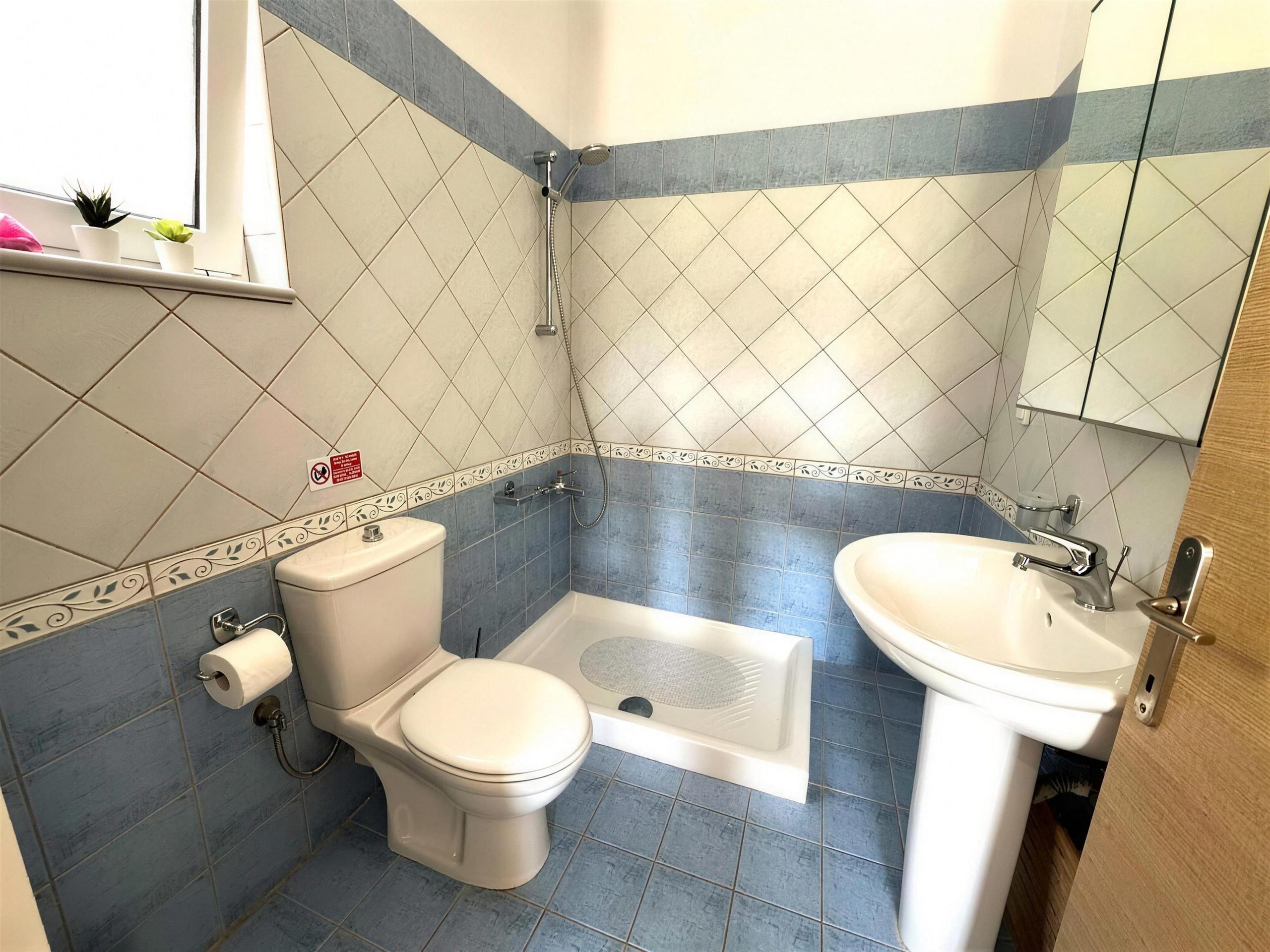A tiled bathroom with a bath, a basin and a mirrored cabinet