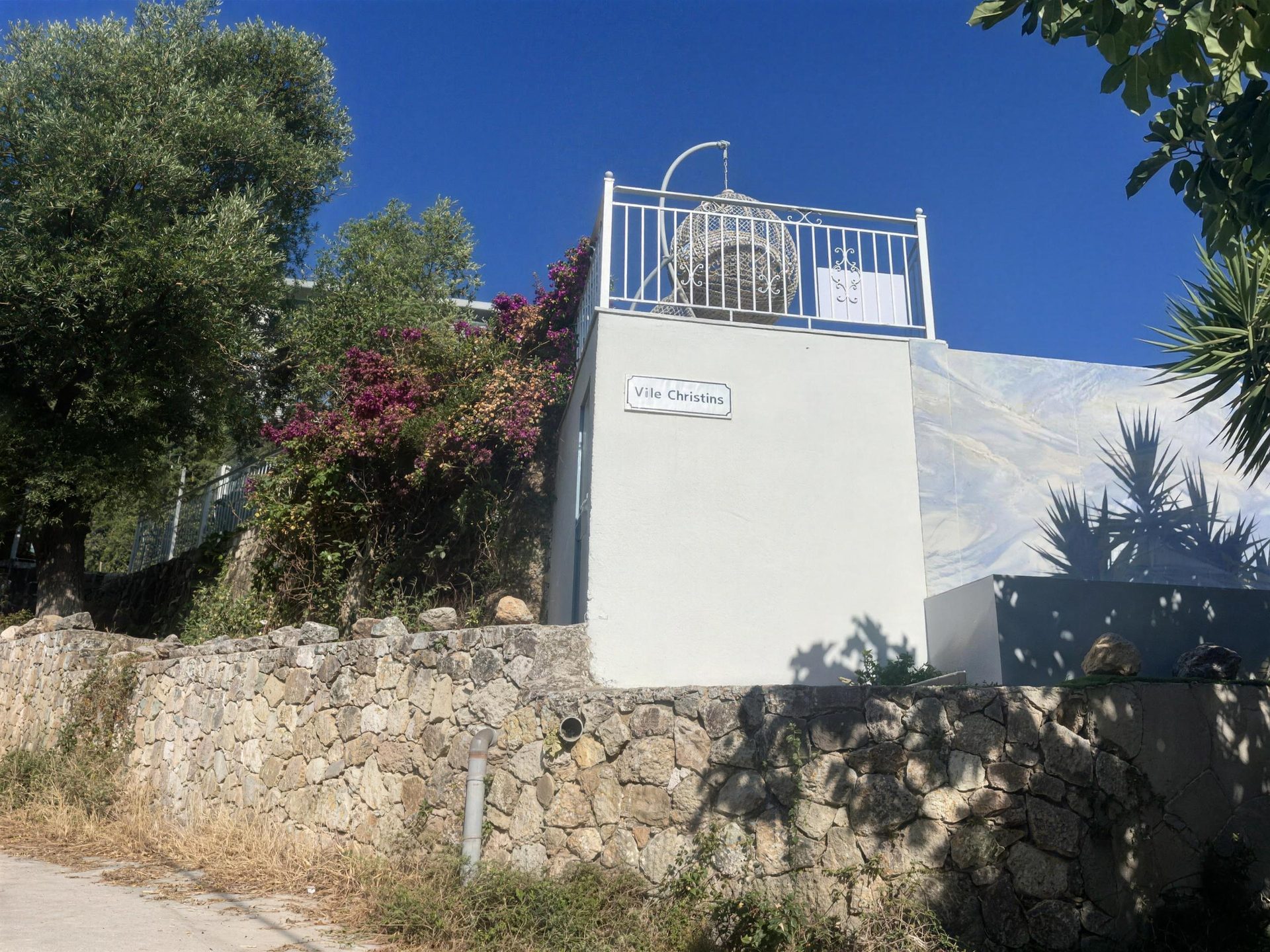 The gate and the villa's own sign, bougainvillea over the wall