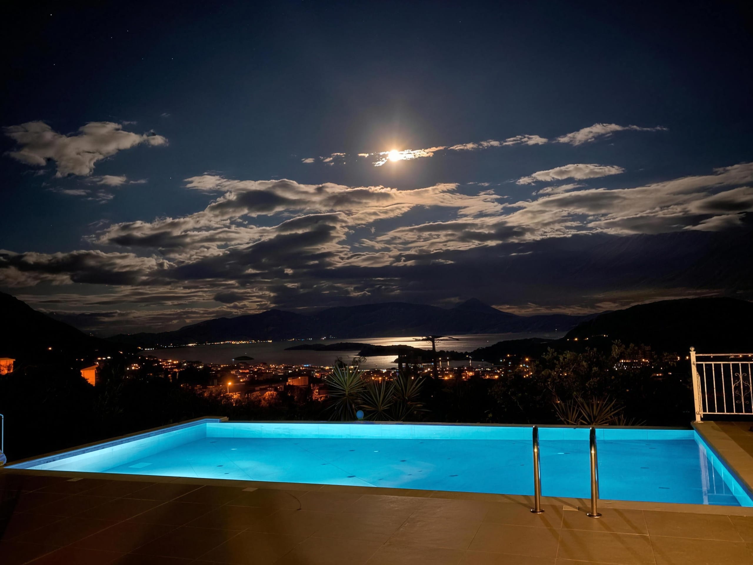 The pool lit at night above Nidri, the moon over the bay