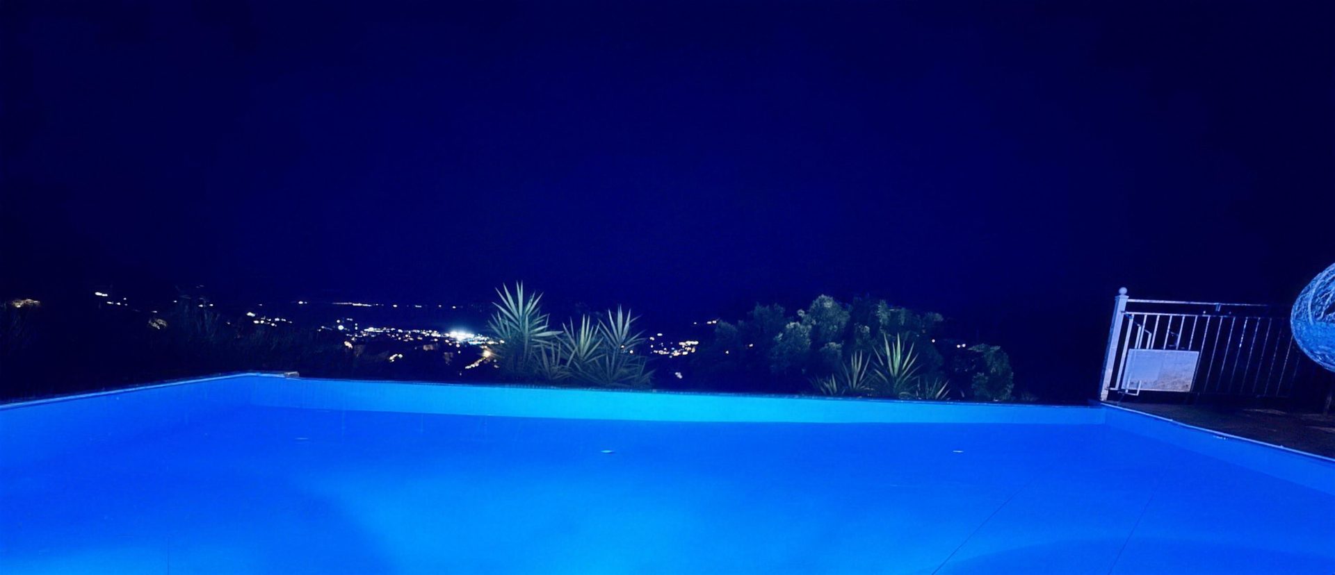 The lit pool after dark, the lights of Nidri strung out along the bay below