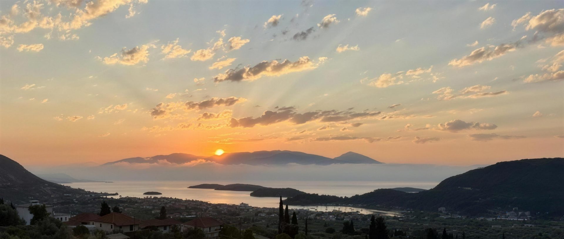 The sun coming up out of Nidri Bay, mist lying on the water and the mainland mountains beyond
