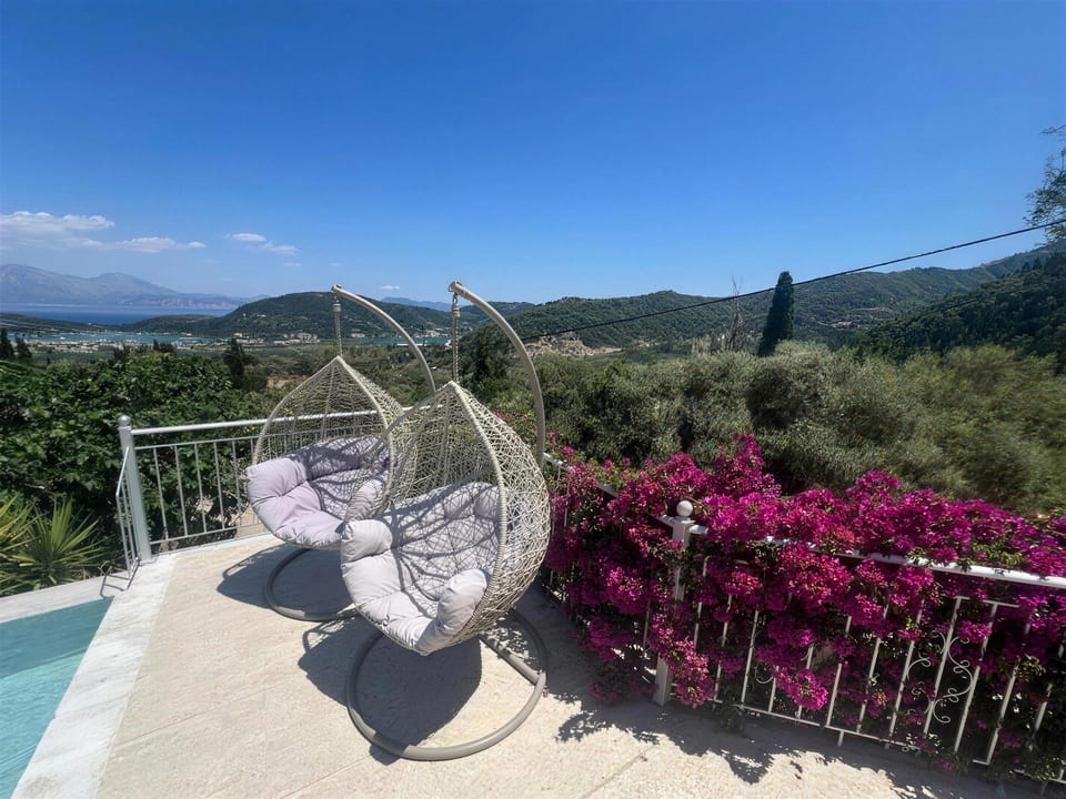 A hanging chair on the terrace, bougainvillea and the bay beyond